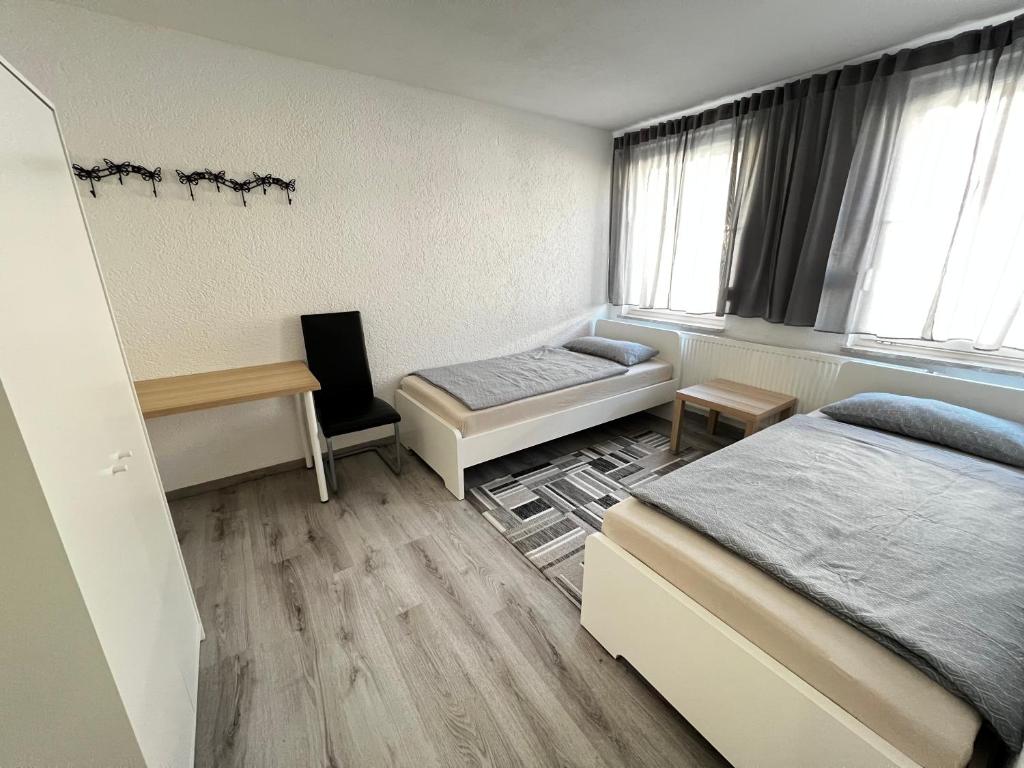 a bedroom with two beds and a desk and window at Wohnung in Oberesslingen