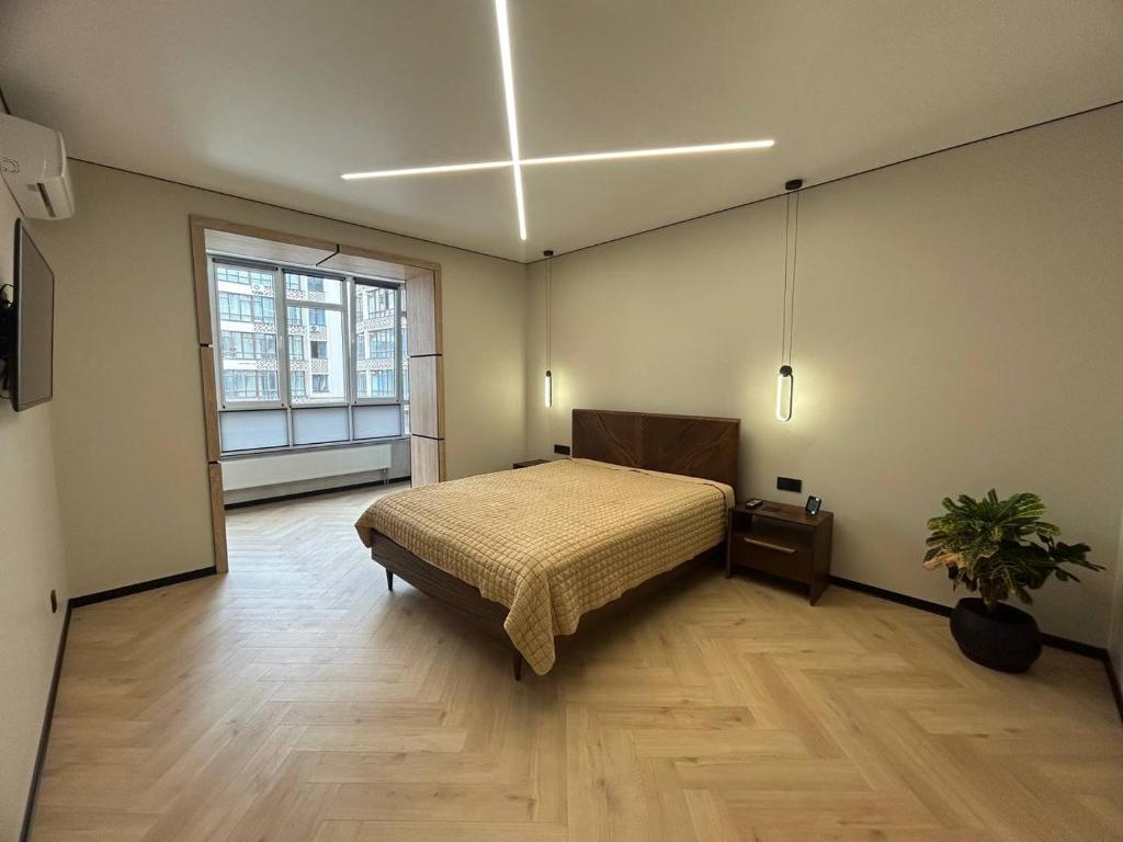 um quarto com uma cama e uma grande janela em Апартаменти в центрі на Проскурівського Підпілля em Khmelʼnytsʼkyy