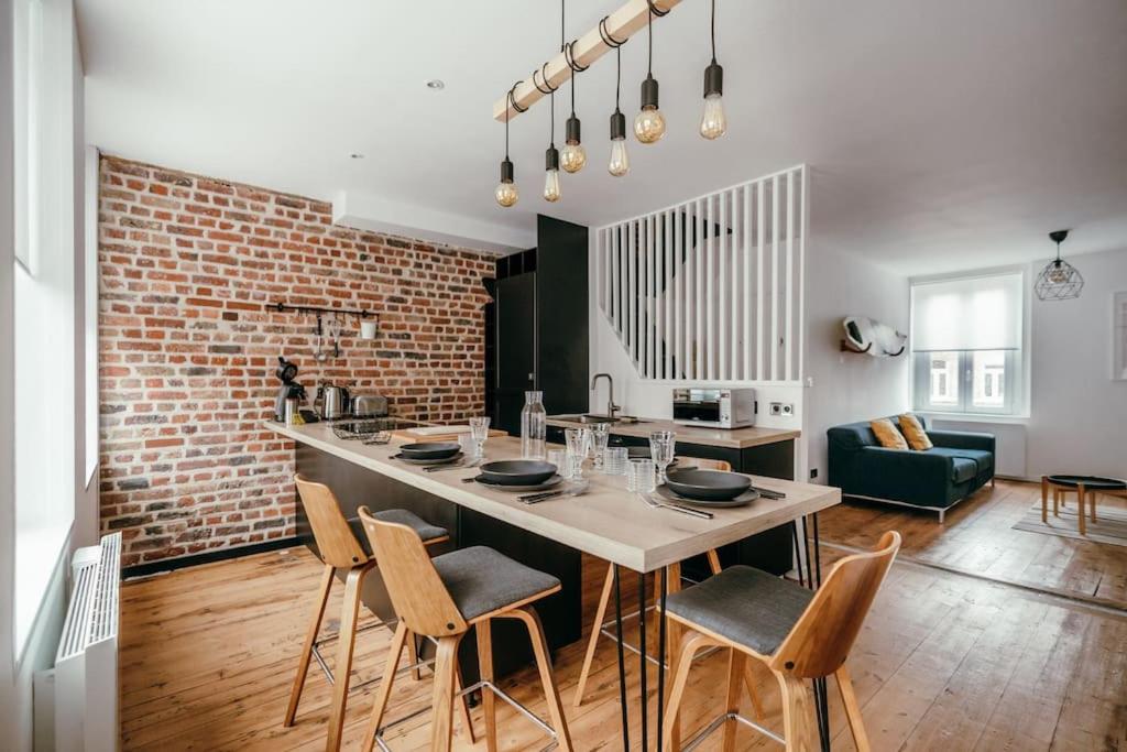 une cuisine avec une table et des chaises ainsi qu'un mur en briques dans l'établissement Duplex 4pers - 100m du métro - SmartTV - Fibre, à Lille