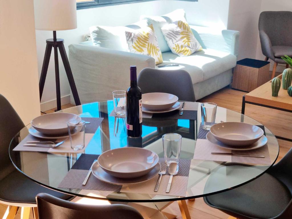 a glass table with a bottle of wine on it in a living room at Arboleda Centro in Soria