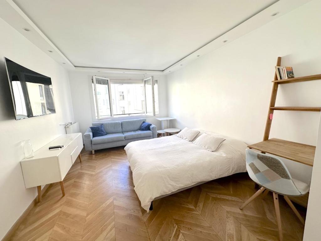 a white bedroom with a bed and a couch at Le Chalgrin in Paris