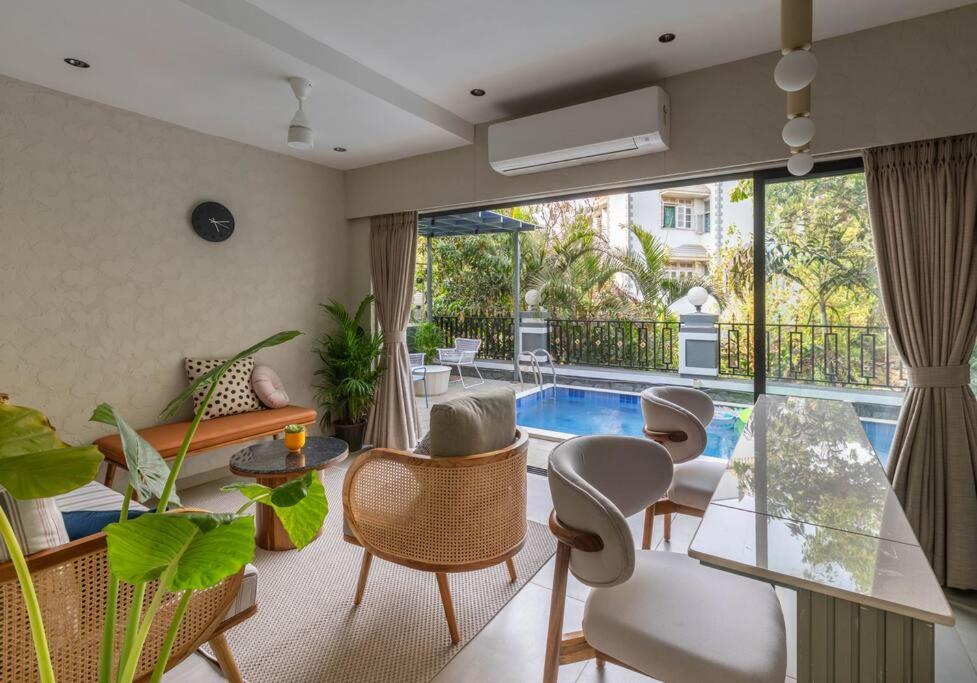 Una sala de estar con mesa y sillas y una piscina. en Soam Villa - Theatre Room, Plunge Pool & Jacuzzi, en Lonavala