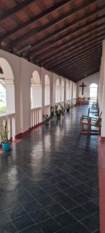 a large room with a black tile floor and a cross at Jesuit Residence in Galle