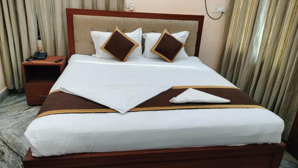 a bedroom with a large white bed with pillows at Hotel Kashyaam Inn in Varanasi