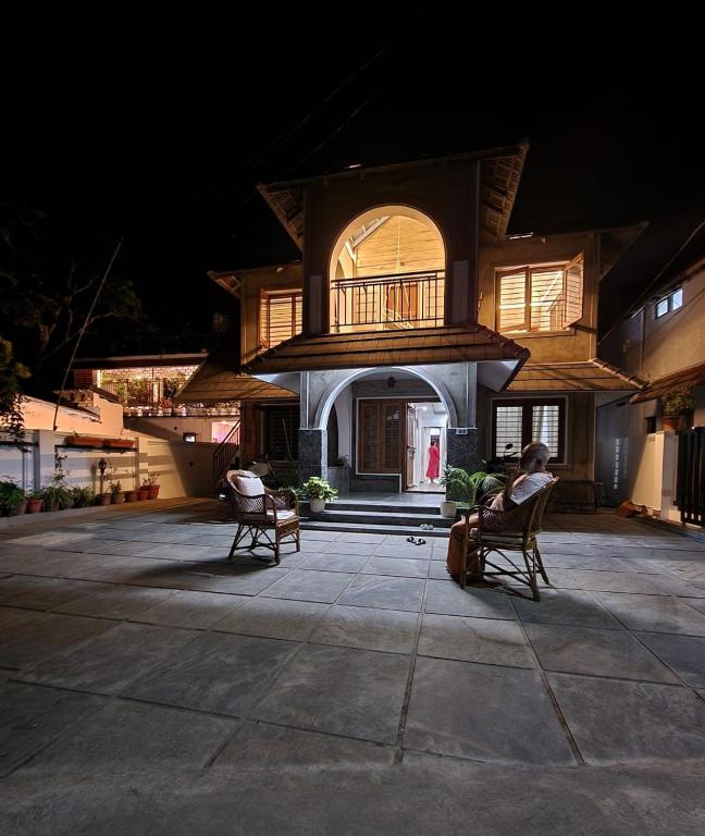 a person sitting in chairs in front of a building at Mickey Homestay in Thekkady