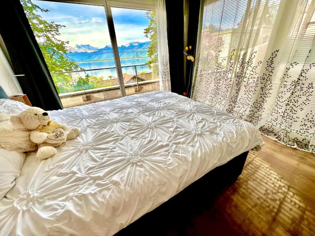two teddy bears sitting on a bed in front of a window at Spa luxury app for 2 or 4 pers centre lac view in Montreux