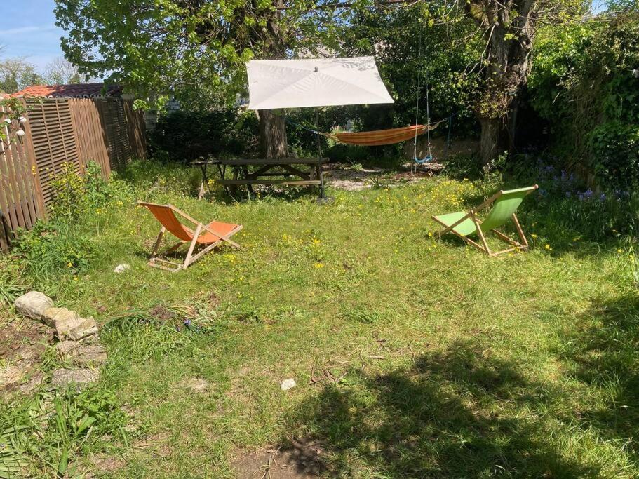 duas cadeiras e uma mesa e um guarda-sol num quintal em Grande maison à 5 minutes des plages em La Rochelle