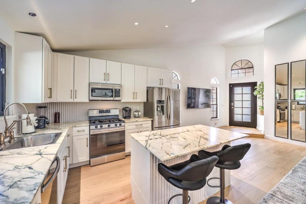 a kitchen with white cabinets and a large island with bar stools at Old Mill - A Bright Modern Green Valley Bungalow in Las Vegas