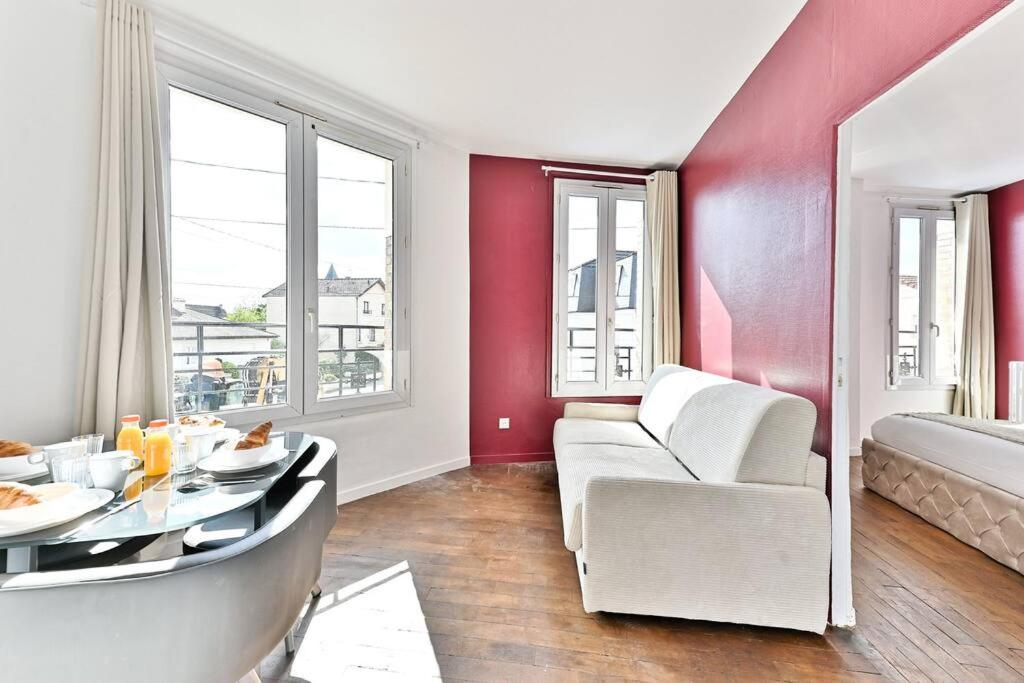 a living room with a white couch and a table at Appartement Rose Moderne Proche de la capitale in Gagny