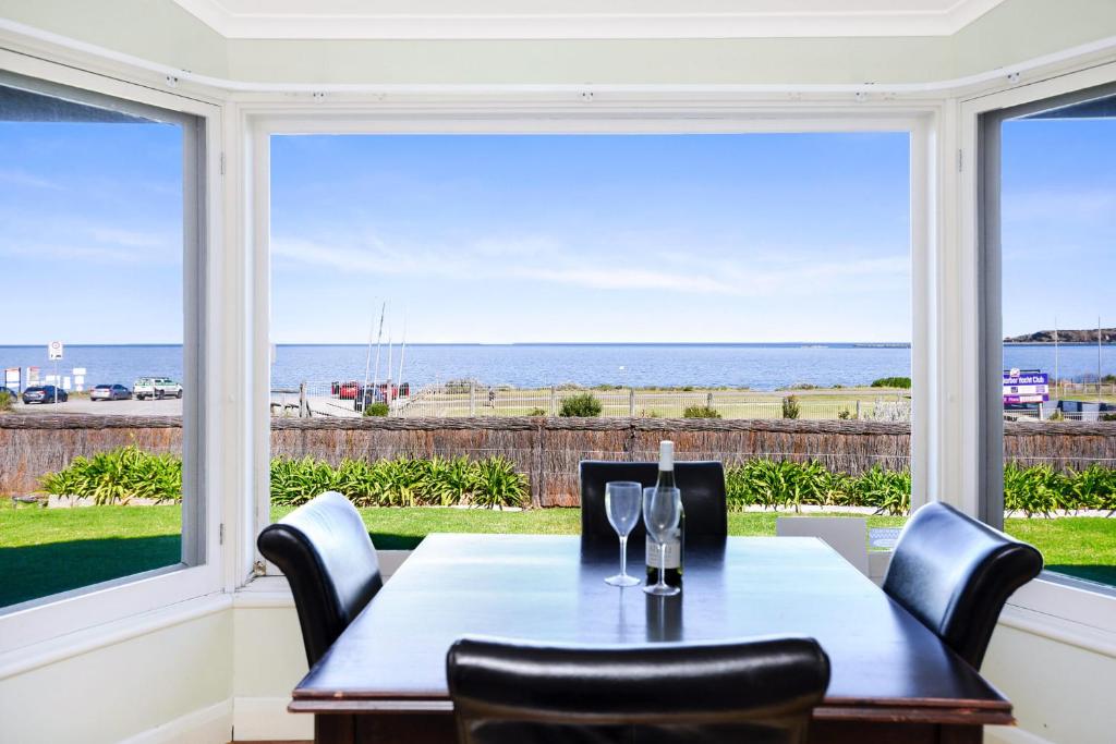 a dining room with a table and chairs and a large window at Beachfront Bliss - Wi-fi Bbq Group House in Victor Harbor