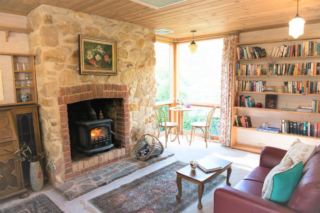 a living room with a stone fireplace and a couch at Adelaide Hills Camellia Cottage Wifi in Crafers