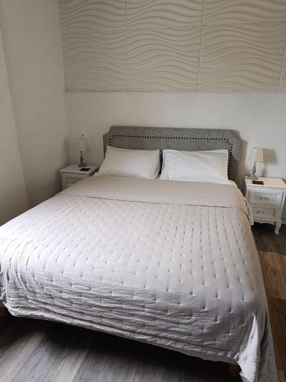 une chambre avec un grand lit blanc avec deux tables de nuit dans l'établissement La Capitelle , Chambre double indépendante avec piscine, à Deaux