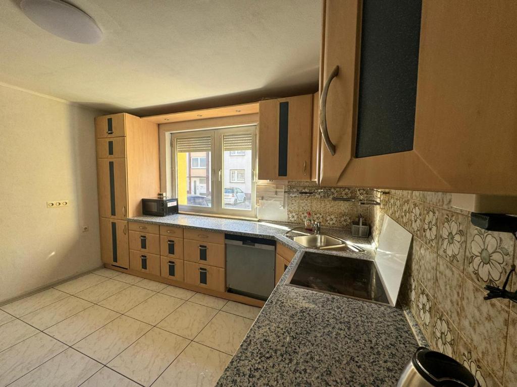 a kitchen with wooden cabinets and a sink and a window at 7 Zimmer Haus in Kaiserslautern in Kaiserslautern