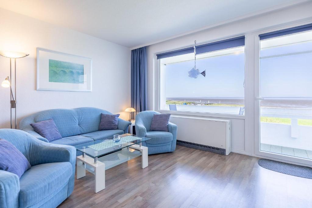 una sala de estar con 2 sofás azules y una ventana grande en Haus Atlantic, FeWo 505 en Döse