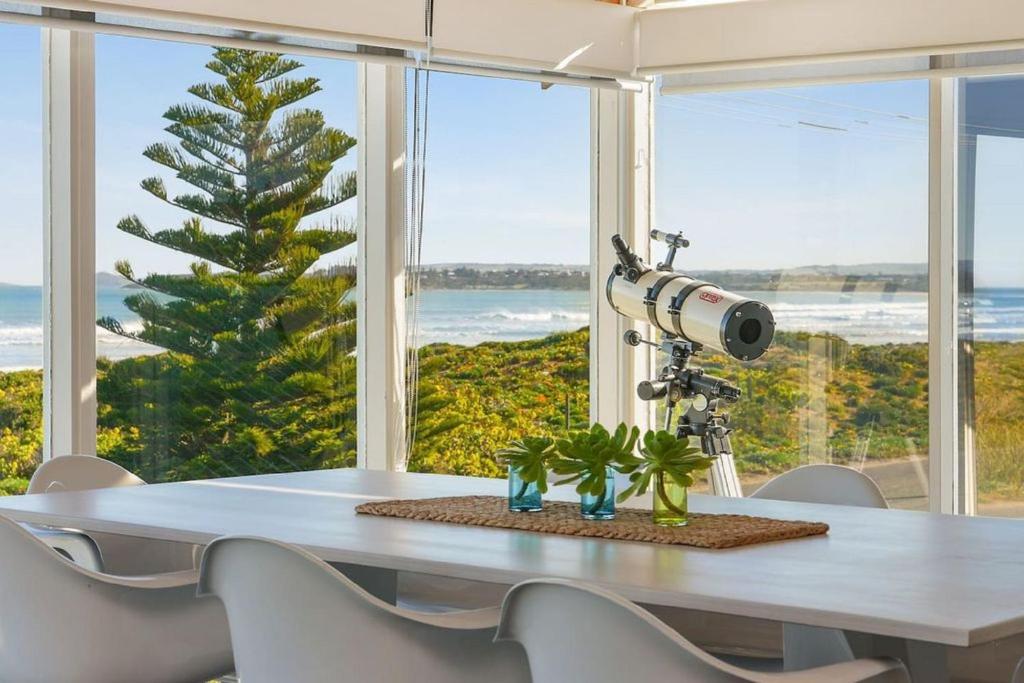 una mesa con una cámara y un trípode frente a una ventana en Glass House By The Ocean Wi-fi, en Middleton