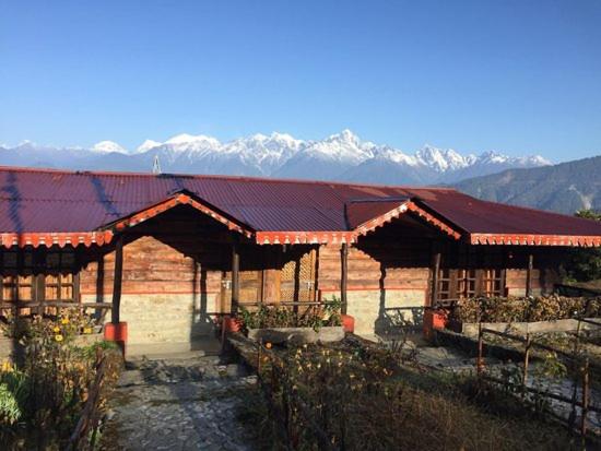 a building with a red roof with mountains in the background at Mt.Narsing Village Resort in Ravangla
