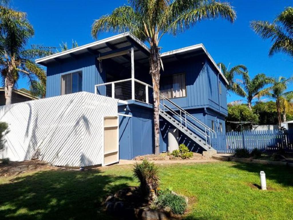 a blue house with palm trees in front of it at Riverglades Murray Bridge in Murray Bridge
