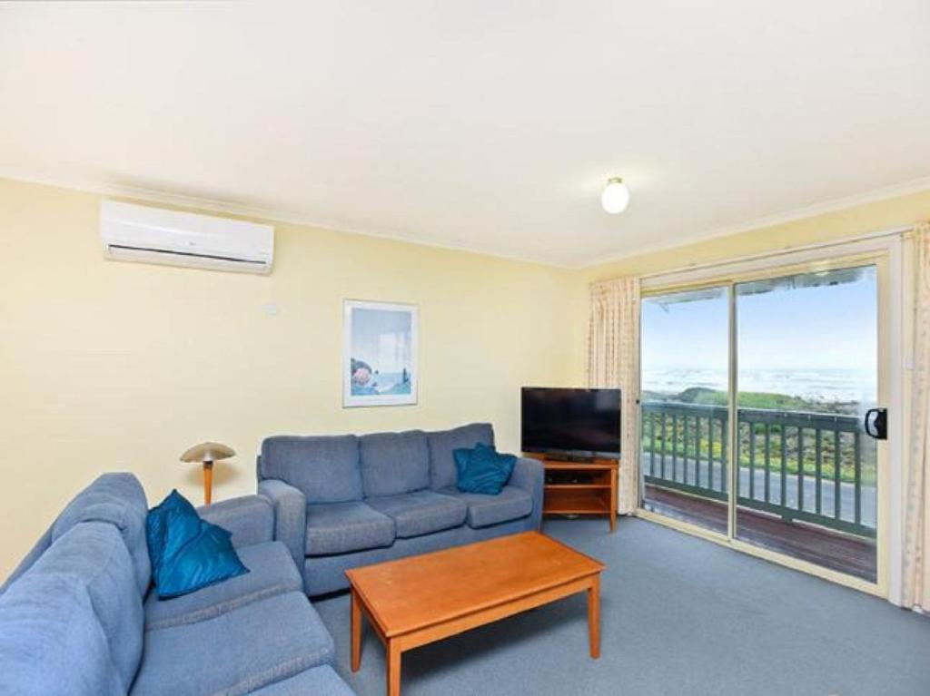 a living room with a blue couch and a television at Tahren Beachfront Shack Wifi - Pet-friendly in Middleton