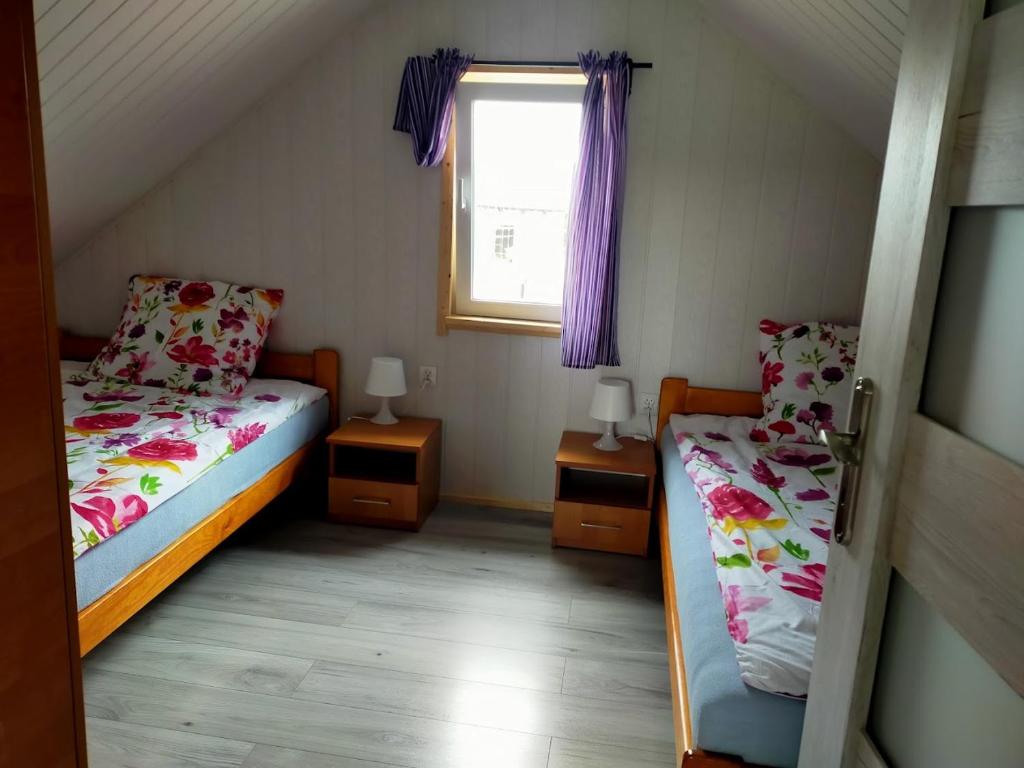a small bedroom with two beds and a window at Domki u Jagodzianki in Smołdziński Las