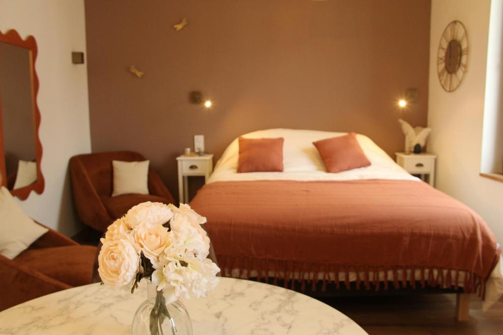 - une chambre avec un lit et une table ornée d'un vase de fleurs dans l'établissement L'Embellie, à Aix-les-Bains
