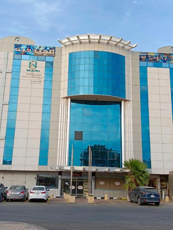 un grande edificio con macchine parcheggiate di fronte di Aldar Hotel a Jazan