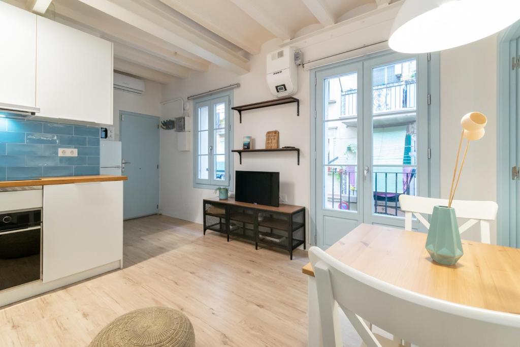 cocina y comedor con armarios blancos y mesa en Apartment Pontevedra 20m from the beach, en Barcelona