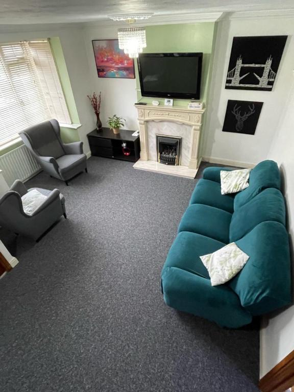 a living room with a blue couch and a fireplace at Lovely 3 bed house with patio/bbq in Slades Green