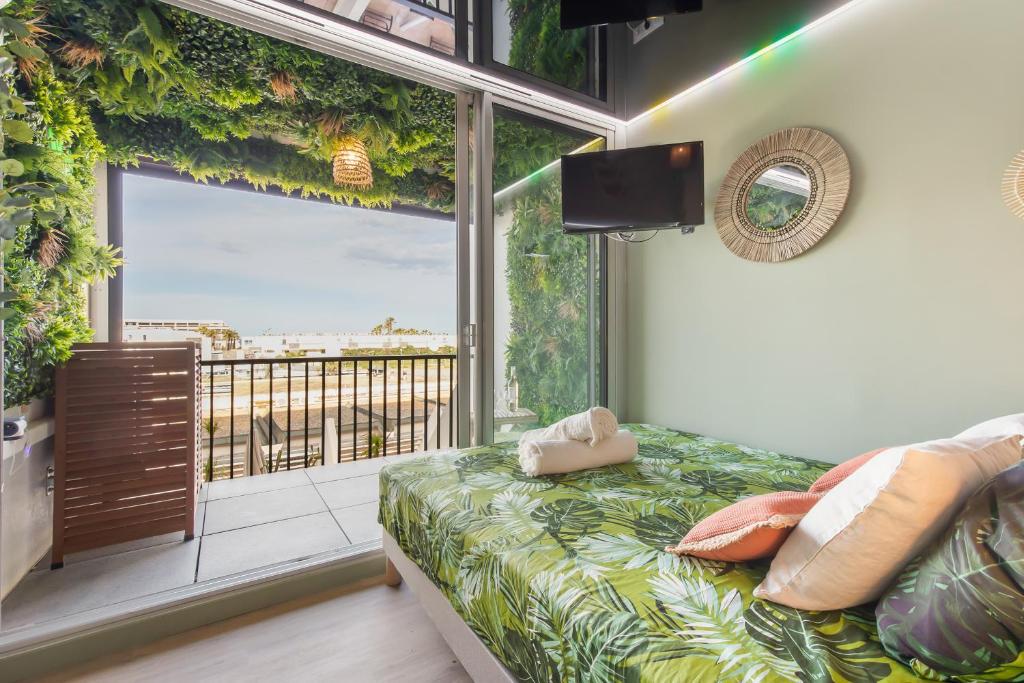 une chambre avec un lit et une grande fenêtre dans l'établissement Jungle House héliopolis, au Cap d'Agde
