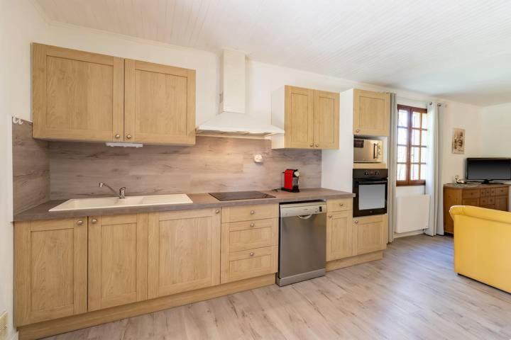 cocina con armarios de madera, fregadero y fogones en maison en Périgord proche Beynac et Sarlat en Cénac-et-Saint-Julien