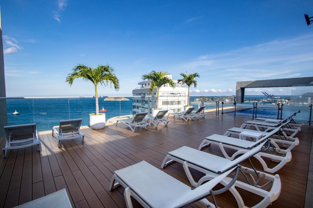 une terrasse avec des chaises longues et l'océan dans l'établissement Hilton Garden Inn Santa Marta, à Santa Marta