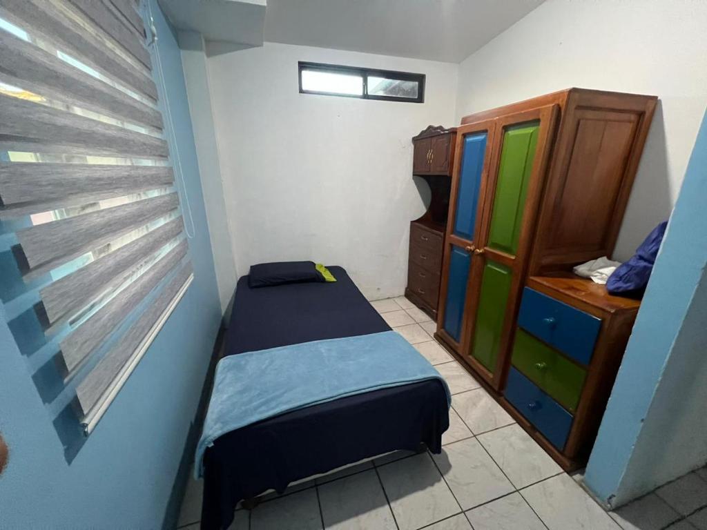 a small bedroom with a bed and a dresser at surf house in Puerto Baquerizo Moreno