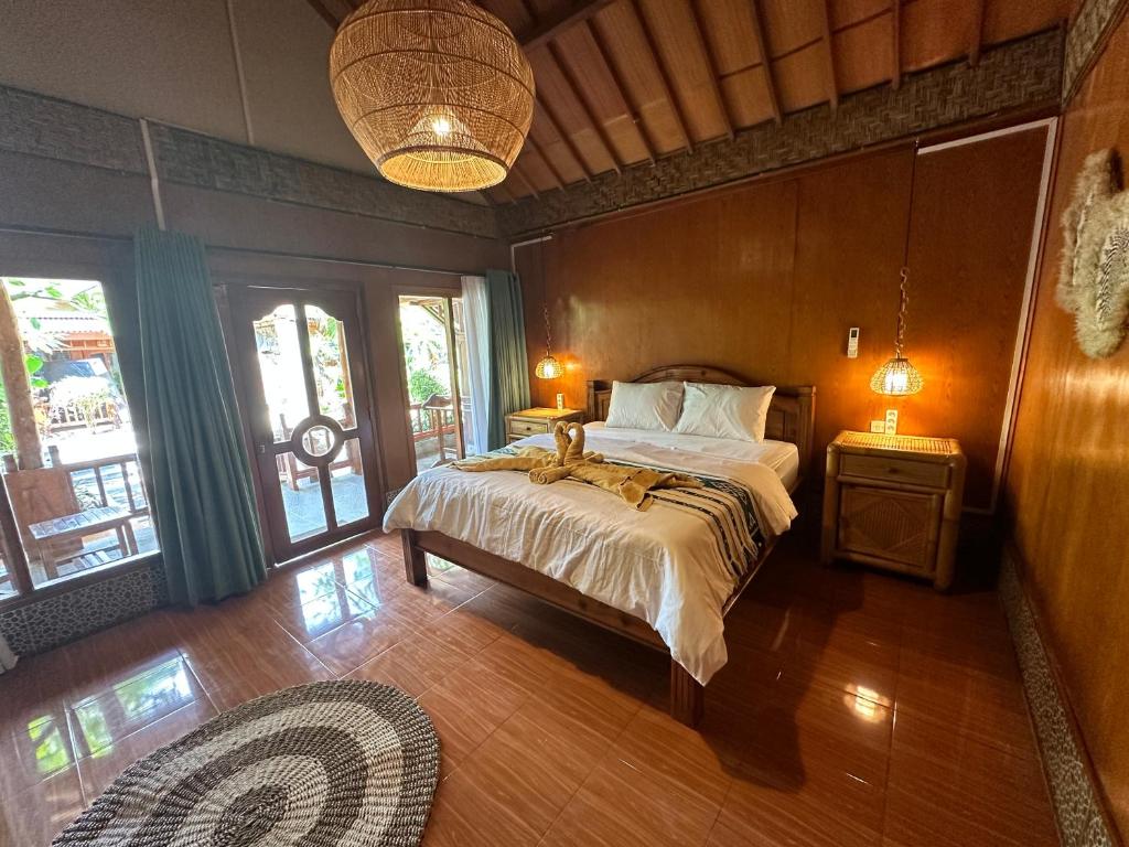 a bedroom with a bed and two lamps and windows at Sunny Rose Bungalows Gili Air in Gili Air