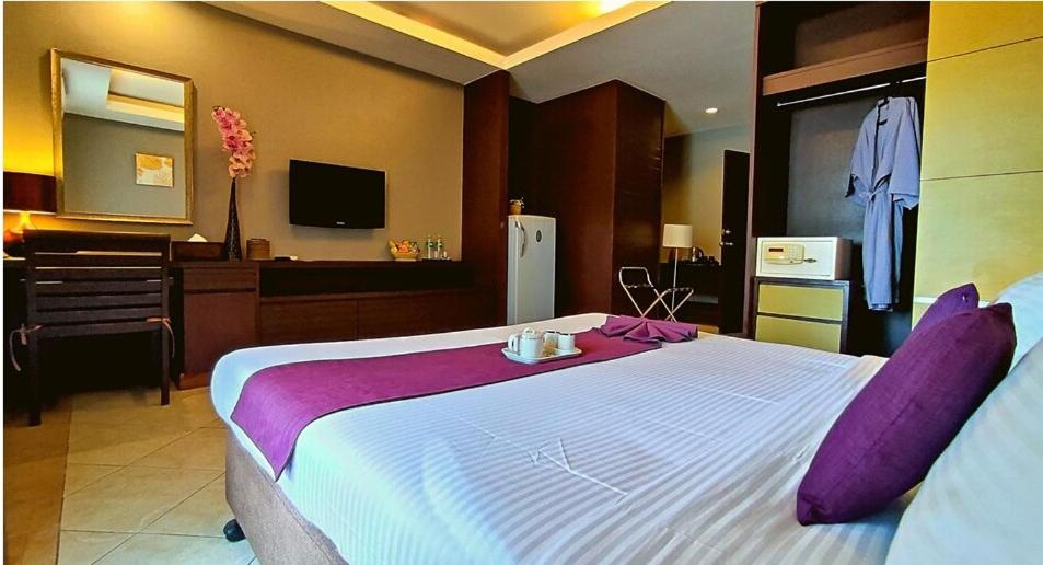 a bedroom with a large white bed with purple pillows at Gazebo Resort, Pattaya in Pattaya