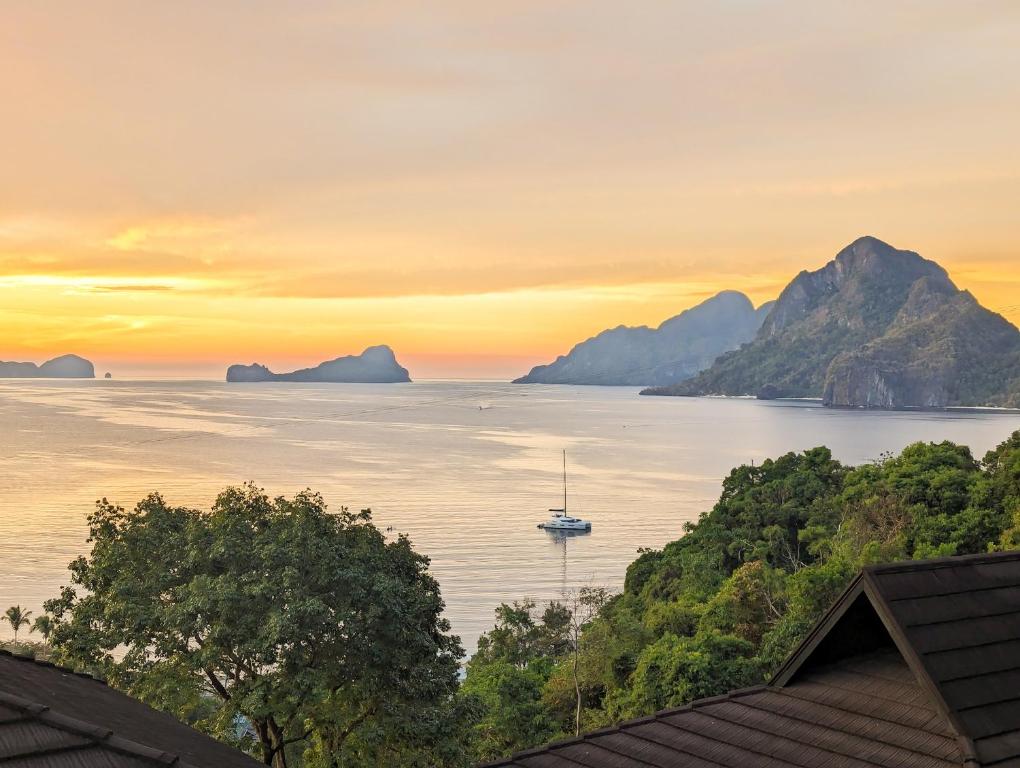 a boat in the water at sunset with mountains at Perch El Nido's Seaview Villas Marimegmeg Beach in El Nido