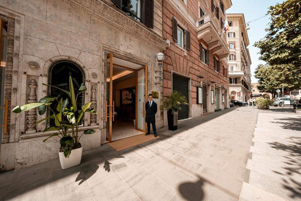 ローマにあるHotel Via Venetoの建物の出入口に立つ服装の男
