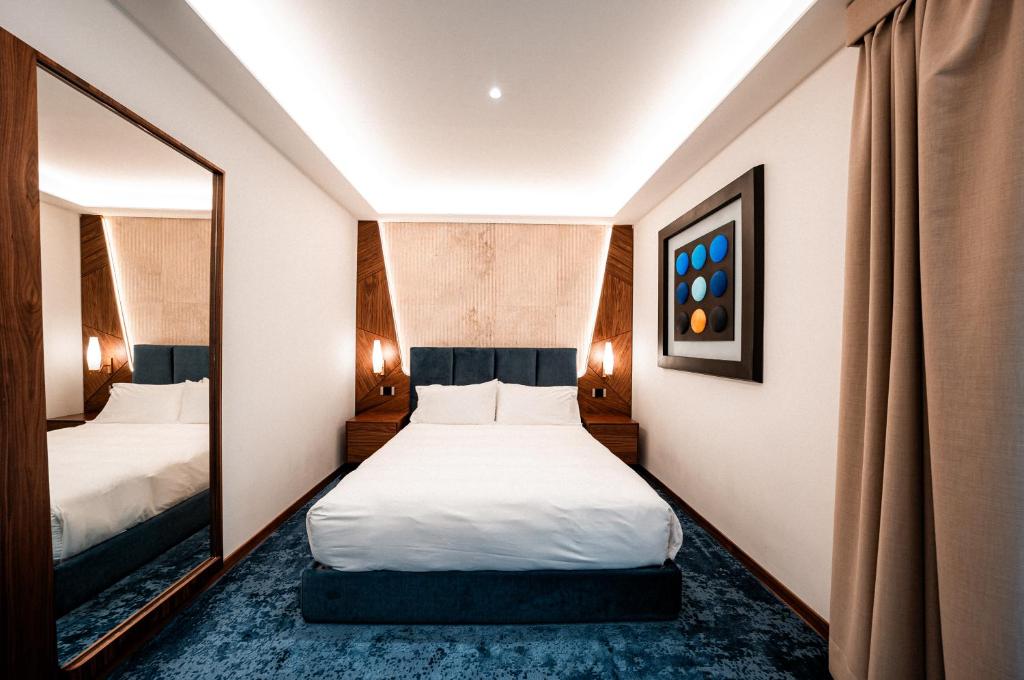 ローマにあるHotel Via Venetoのベッドが2つと鏡があるホテルの部屋