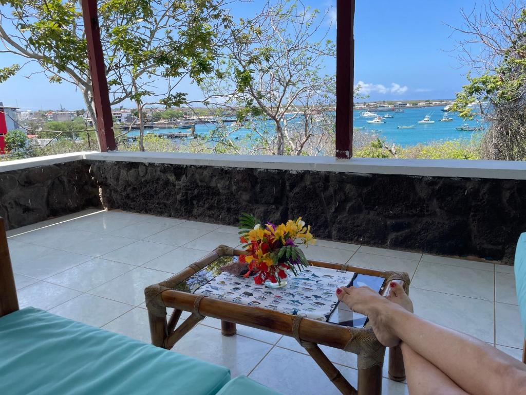 a person sitting on a balcony with a table with flowers at Casa Verde Vacation Garden Home in San Cristóbal