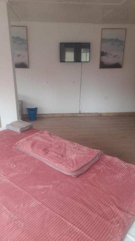 Una cama con una manta rosa encima. en HOTEL JIMENA, en Iquique
