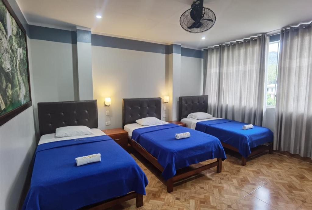 two beds in a room with blue sheets at Hotel Su Majestad in Tingo María
