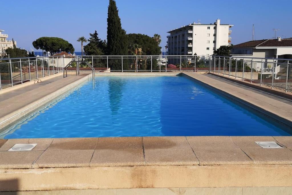 une grande piscine bleue dans une ville dans l'établissement Terrasse ensoleillée et accès à la piscine vue mer, à Vallauris