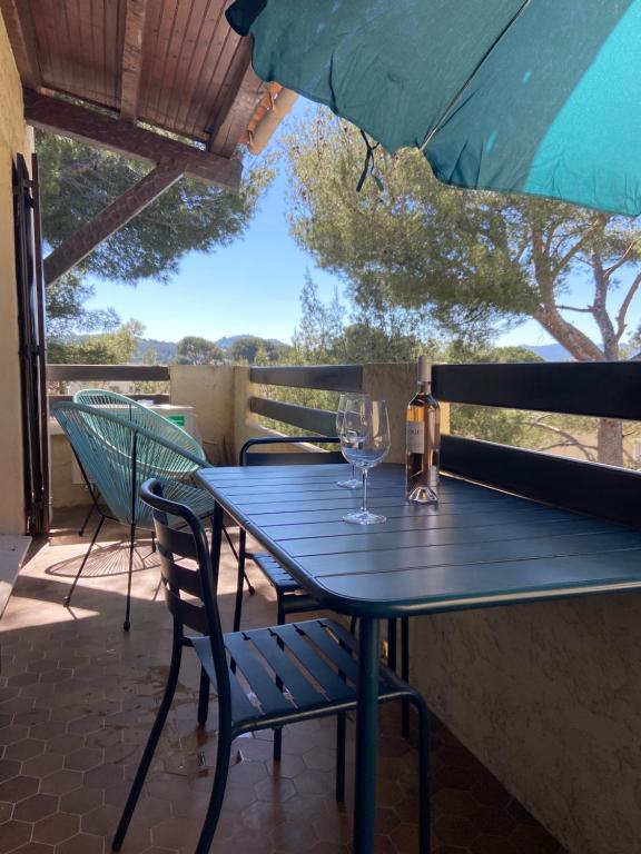 une table bleue avec un verre de vin sur une terrasse dans l'établissement T2 tout confort et moderne, climatisé avec balcon et parking, à 10 min du port et de la plage, à Sanary-sur-Mer