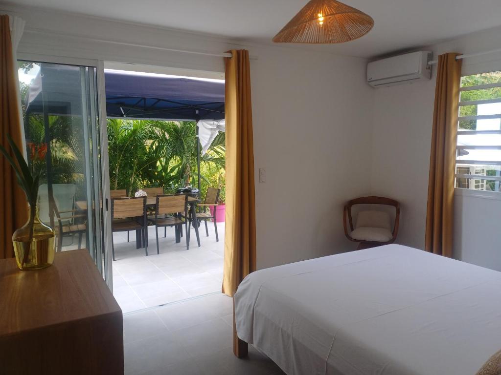 a bedroom with a bed and a balcony with a table at F3 Le Carbet des Anges in Le Carbet