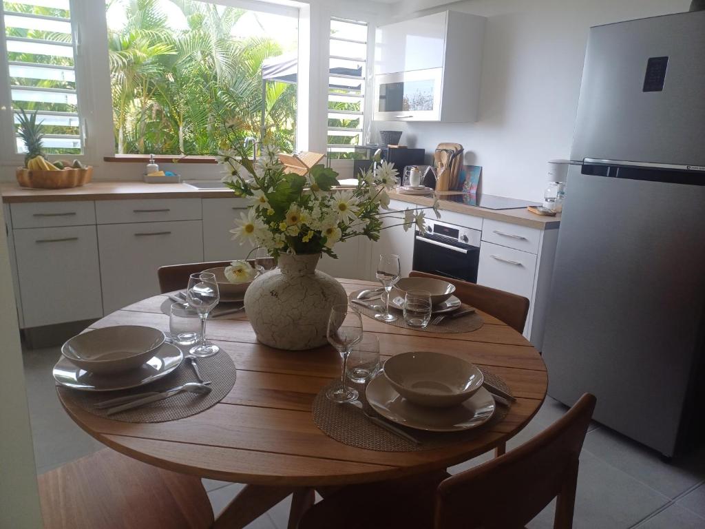 a kitchen with a wooden table with a vase of flowers at F3 Le Carbet des Anges in Le Carbet