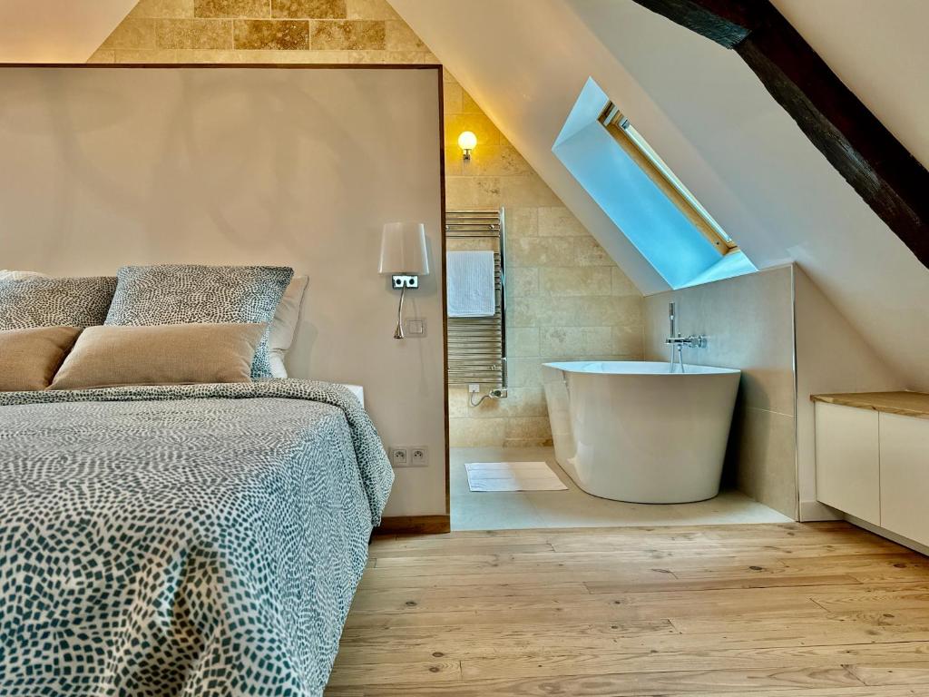 a bedroom with a bed and a bathroom with a tub at Le Loft - By BEST KEYS - Prestige - Vue Cathédrale - Poutres Apparentes - Baignoire Îlot - Centre Ville - Smart TV - Machine à Café Nespresso - WiFi Illimité - Check-in Autonome in Sens