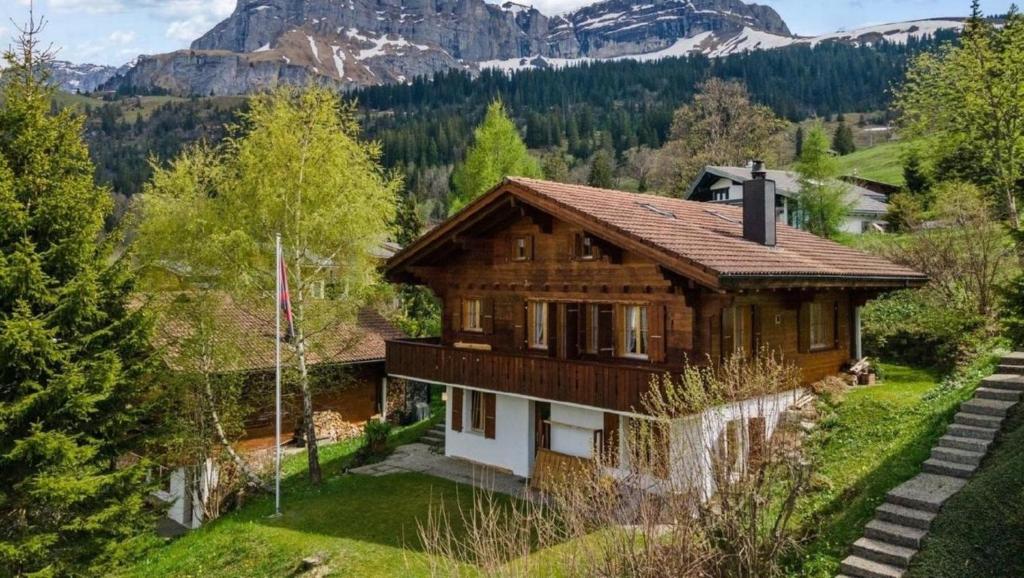 una casa de madera con una montaña en el fondo en Chalet Specht, gemütliches Ferienchalet auf der Axalp, en Axalp