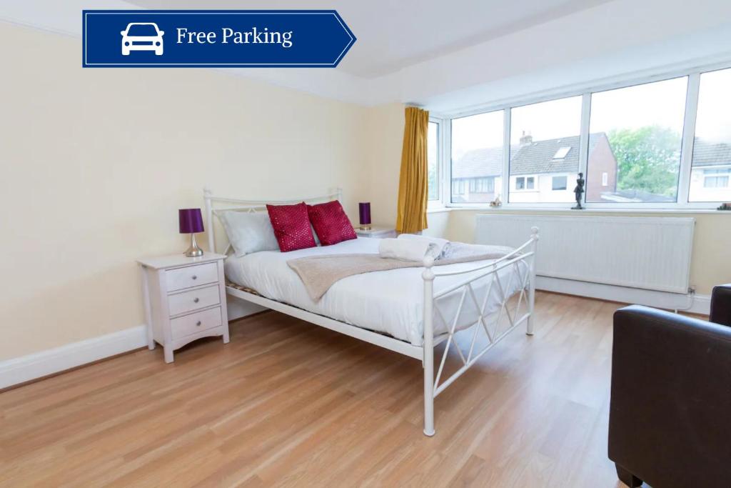 um quarto com uma cama branca e almofadas vermelhas em Spacious 2BR Home with Free Parking em Penwortham