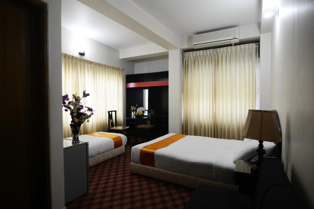 a hotel room with two beds and a table with flowers at Holiday Xpress in Dhaka