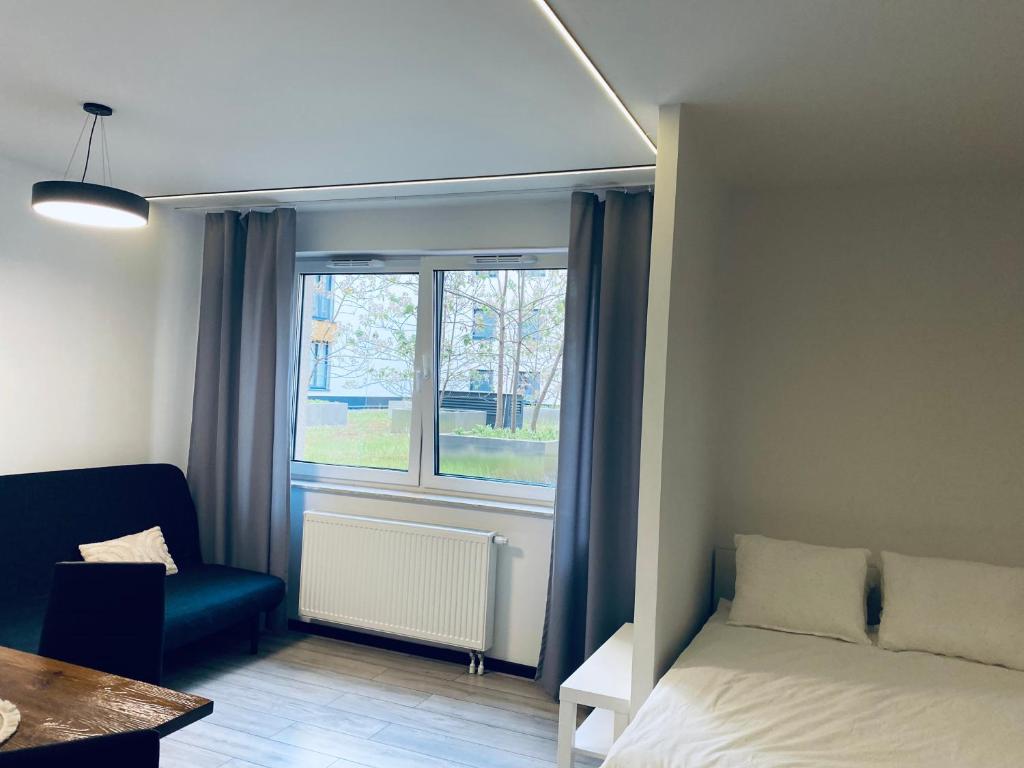 een slaapkamer met een bed, een raam en een stoel bij Enes Apartments Legnicka Street 59D in Wrocław