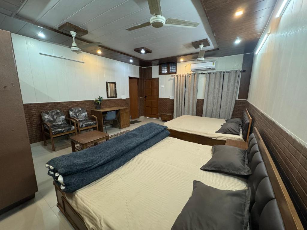 Cette grande chambre comprend deux lits et une table. dans l'établissement S.J. Homestay, à Dehradun