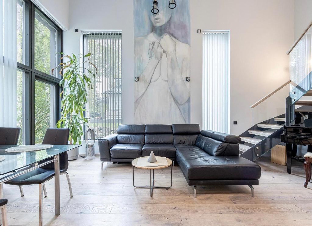 a living room with a black leather couch and a painting at Villa David in Espoo